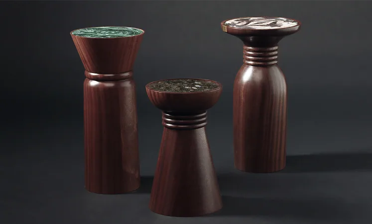 Three turned-wood pedestals topped with malachite and jasper, on a dark ground.