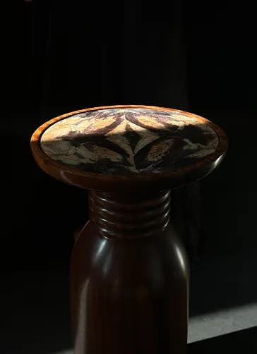 Pedestal with a jasper mosaic top, lit dramatically against darkness.