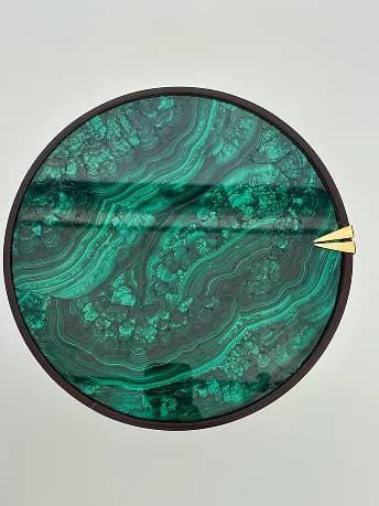 Overhead view of a circular malachite tabletop with a gold detail.